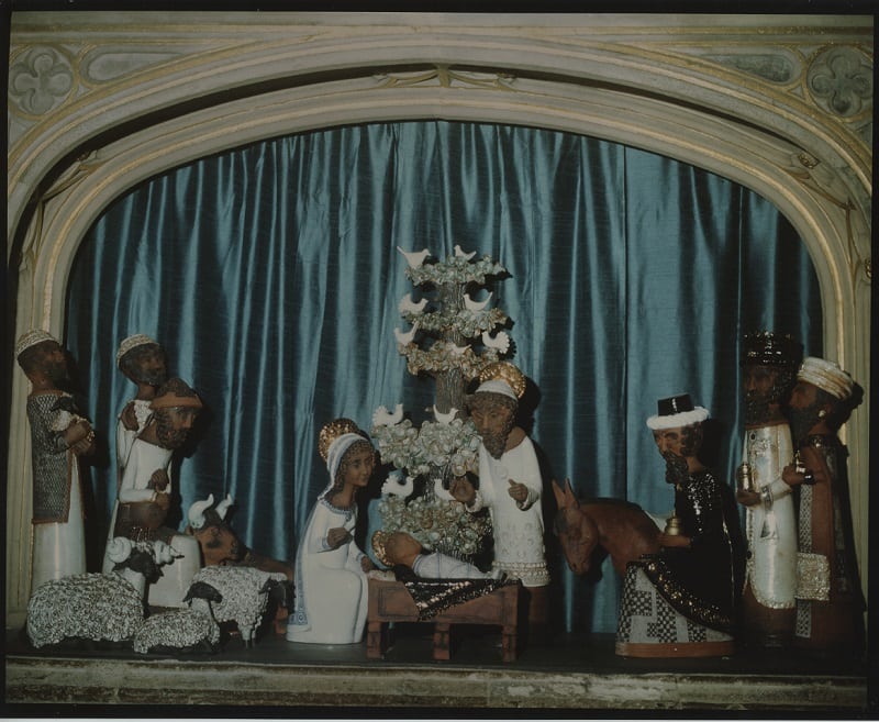 A nativity scene. The baby Jesus is in the crib at the centre surrounded by Mary and Joseph and, to the left, three shepherds and their sheep and, to the right, three wise men bearing gifts. 