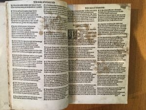 A row of large paw prints cross a page of a 1542 edition of The Canterbury Tales