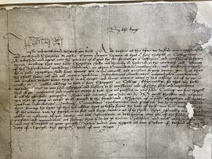 Handwritten document in black ink in secretary hand on grey paper. The paper is torn away at the right-hand edge.