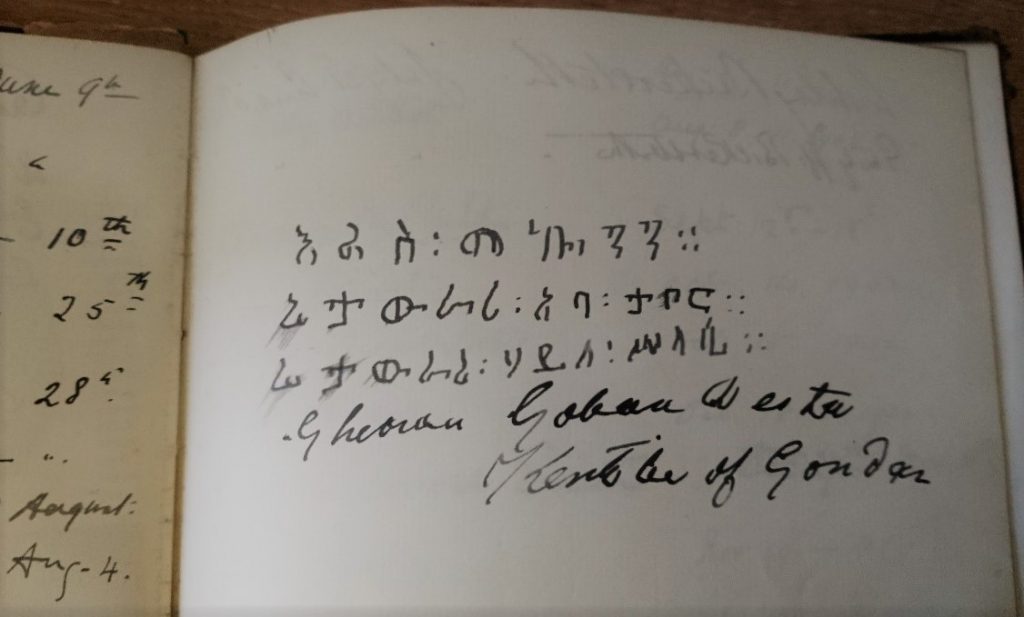 A handwritten message in black ink on white paper. The first three lines are in Ge'ez script and the last two lines are in Latin script. On the left hand side dates are visible from entries on the previous page.