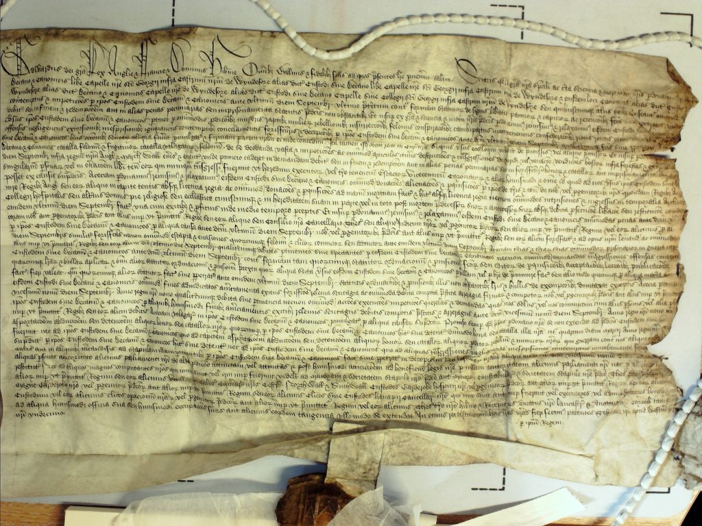 Rectangular parchment document with a seal attached by a tag. The document shows signs of age and damage. The text is handwritten.